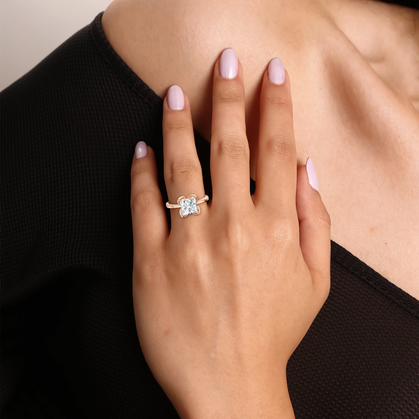 A modern solitaire ring worn gracefully, its structured brilliance enhanced by the soft pink hue of rose gold.